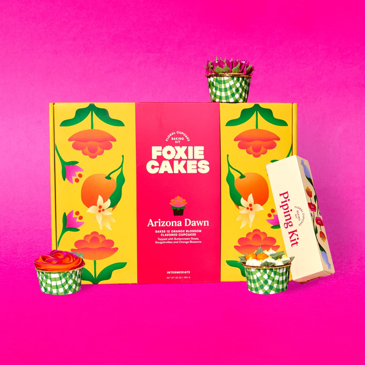 Image of the Better Together Bundle: Foxiecakes Arizona Dawn floral cupcake baking kit box displayed with expansion piping kit and three decorated orange blossom flavor cupcakes featuring bougainvillea, orange blossom and rose-style buttercream frosting, on a pink background. Beginner-friendly DIY cupcake decorating kit for a creative at-home baking experience