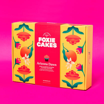 Foxiecakes Arizona Dawn intermediate floral DIY cupcake baking kit box featuring vibrant yellow and pink floral packaging, designed to make 12 orange blossom flavored cupcakes with bougainvillea, orange blossom and rose-style buttercream frosting, ideal for at-home baking, gifting, and creative dessert decorating experiences