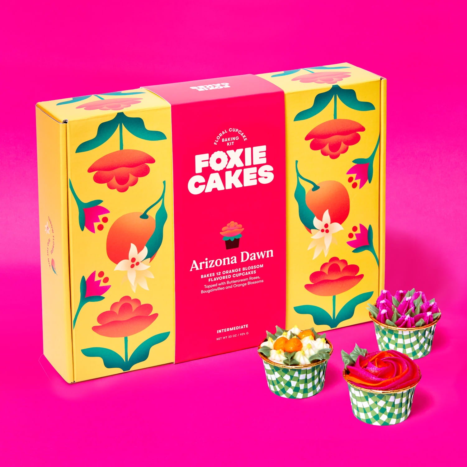 Foxiecakes Arizona Dawn floral cupcake baking kit box displayed with three decorated orange blossom flavor cupcakes featuring bougainvillea, orange blossom and rose-style buttercream frosting on a pink background, beginner-friendly DIY cupcake decorating kit for a creative at-home baking experience