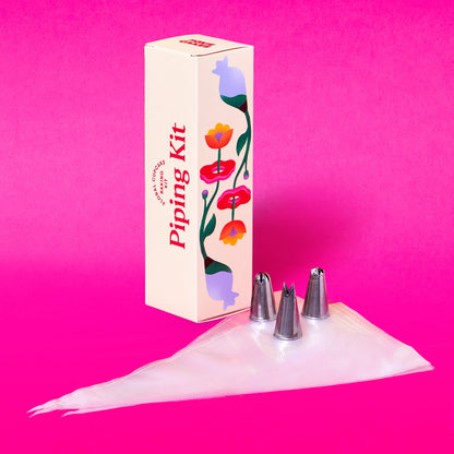Arizona Dawn expansion piping  kit with piping bags and three metal piping tips with a decorative box on a pink background